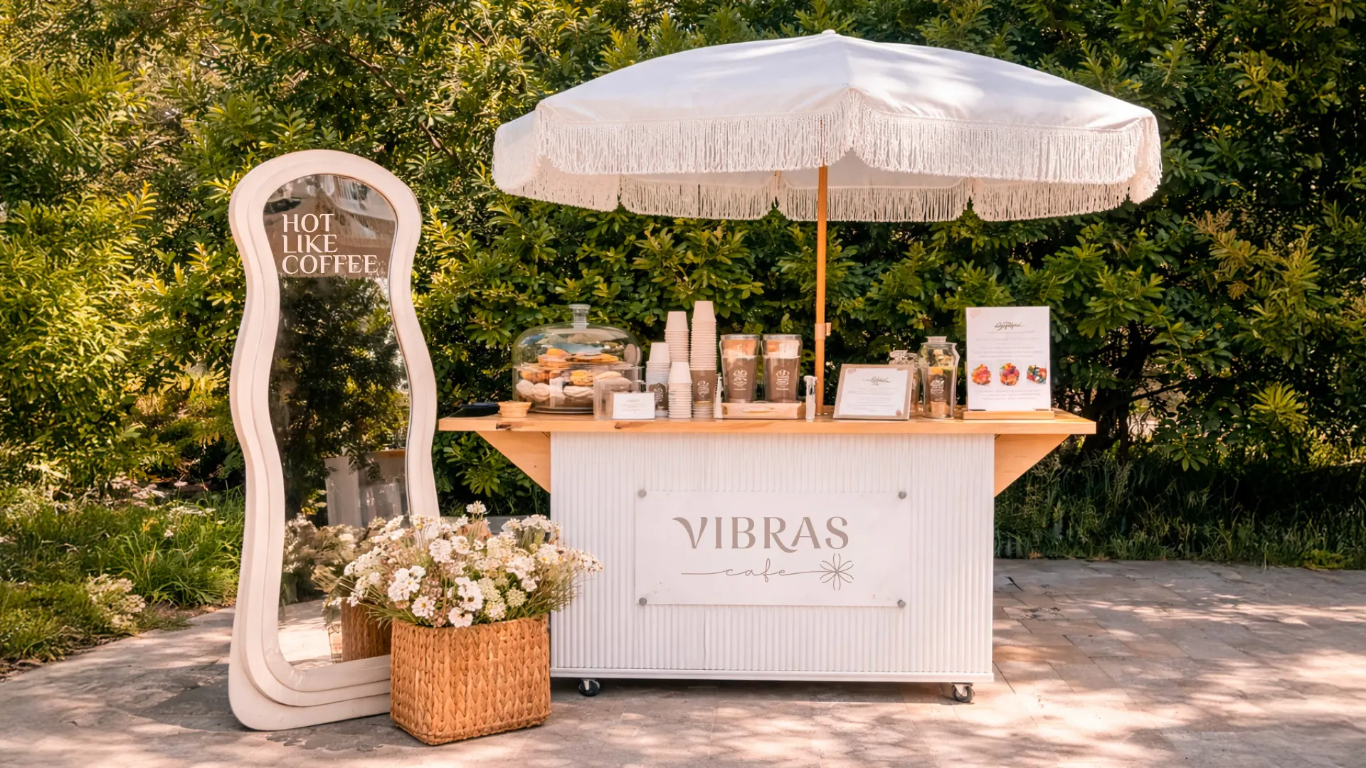 Carrito de café Vibras con sombrilla de flecos y flores en un jardín